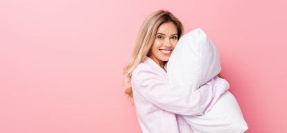 Content woman comfortably hugging a pillow, illustrating improved sleep quality after receiving sleep apnea treatment from our Rockwall dentist.